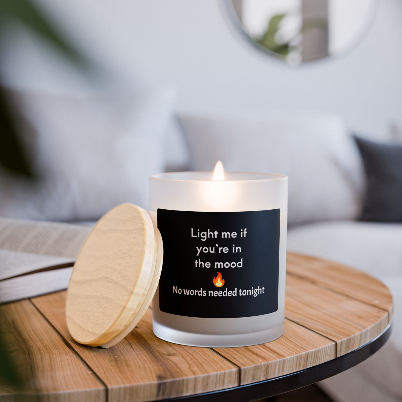 Candle with a humorous message on a wooden table in a cozy living room setting